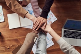 Employees putting their hands in the middle ready to do a cheer
