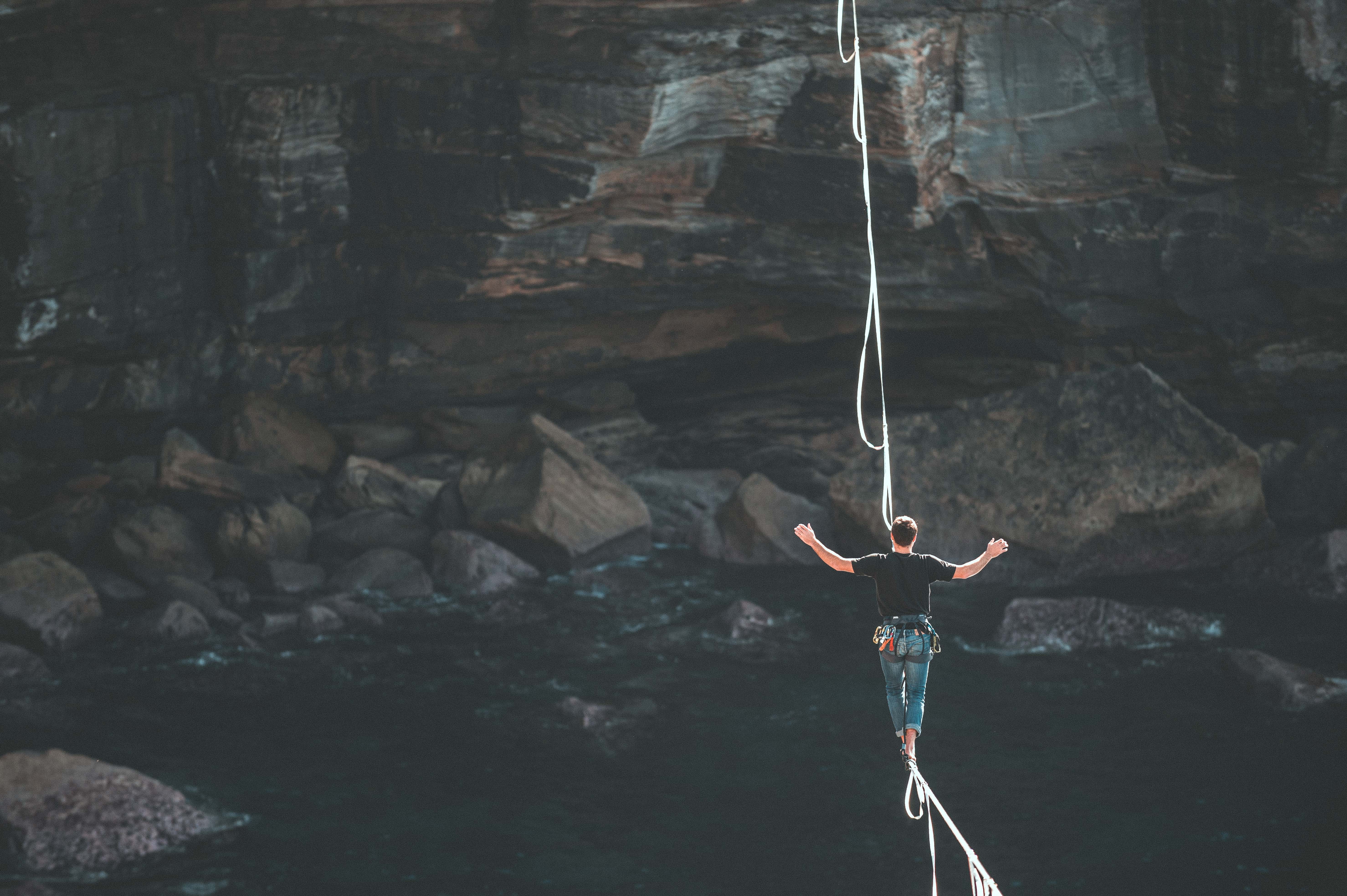 man walking on a slackline across a canyon